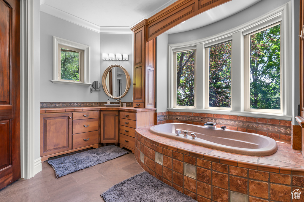 Full bath with plenty of natural light, vanity, a bath, and ornamental molding