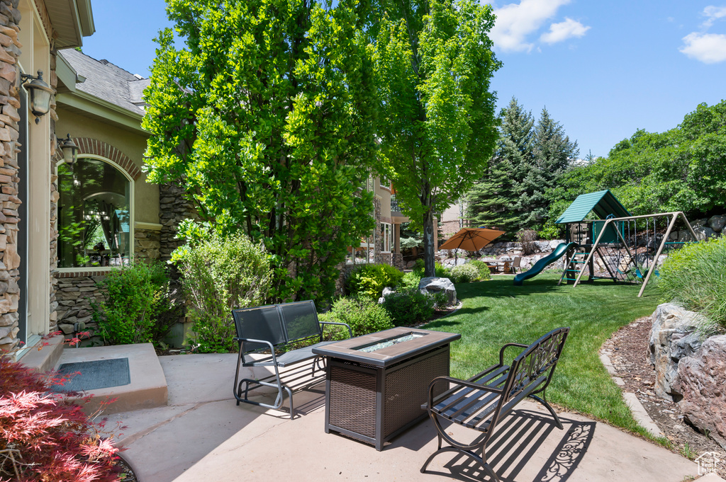 View of patio featuring a playground and an outdoor fire pit