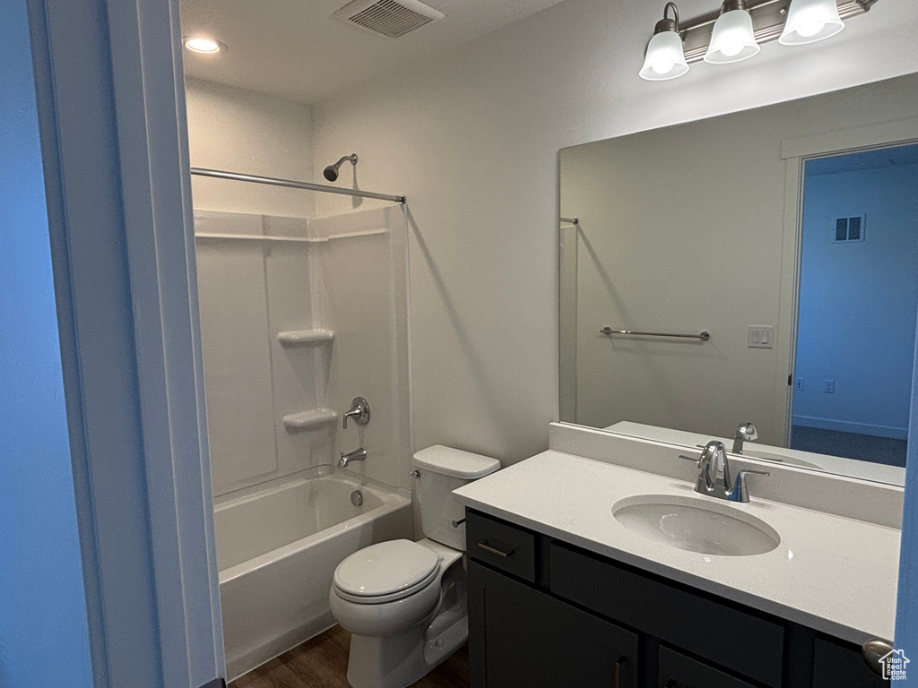 Bathroom with toilet, vanity, wood finished floors, and bathtub / shower combination