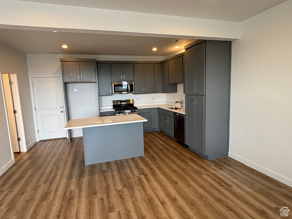 Kitchen featuring appliances with stainless steel finishes, baseboards, recessed lighting, a sink, and wood finished floors