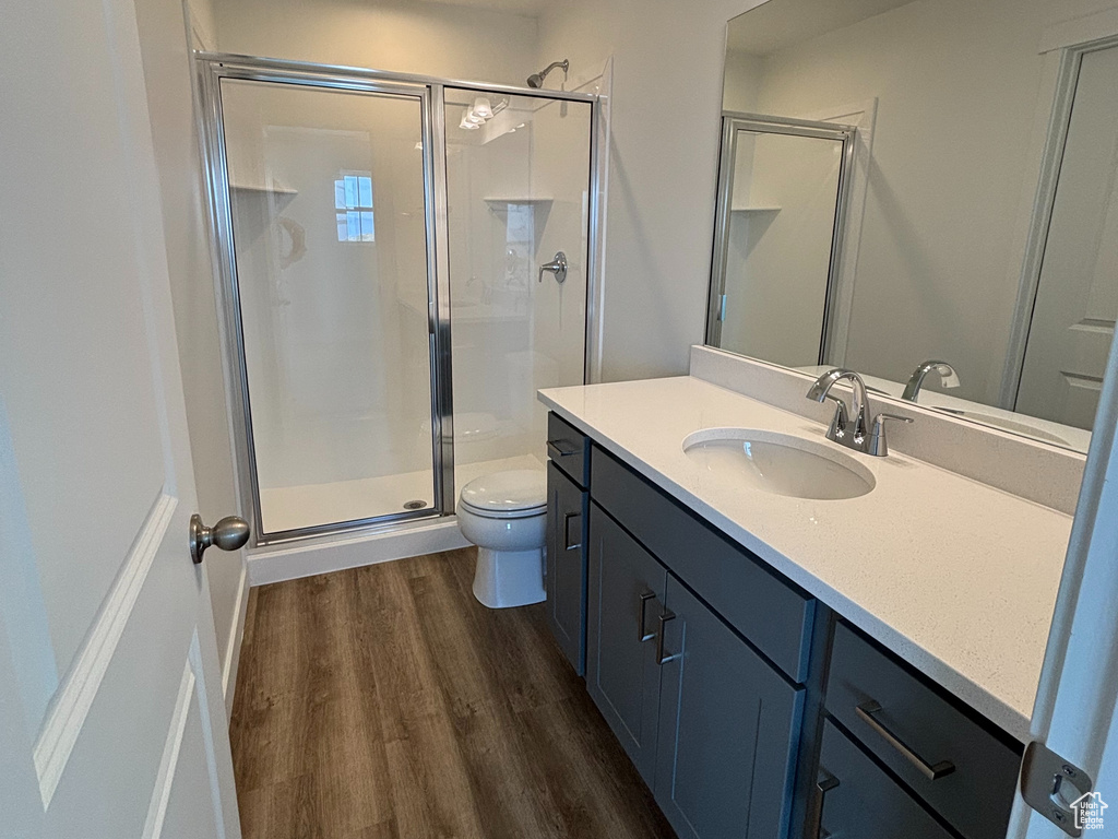 Bathroom featuring toilet, a shower stall, vanity, wood finished floors, and recessed lighting