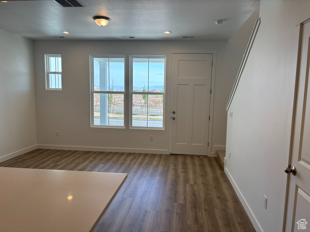 Entrance foyer with dark wood finished floors, baseboards, and a textured ceiling