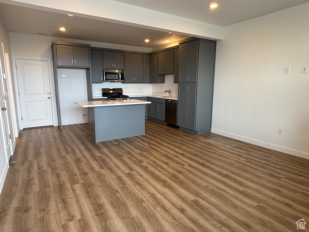 Kitchen with stainless steel microwave, range, black dishwasher, baseboards, and dark wood finished floors