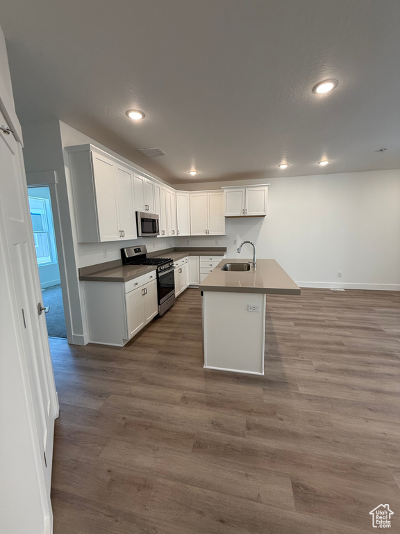 Kitchen featuring appliances with stainless steel finishes, a sink, baseboards, recessed lighting, and white cabinets