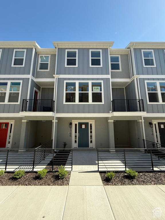 View of property featuring board and batten siding, a balcony, and stucco siding