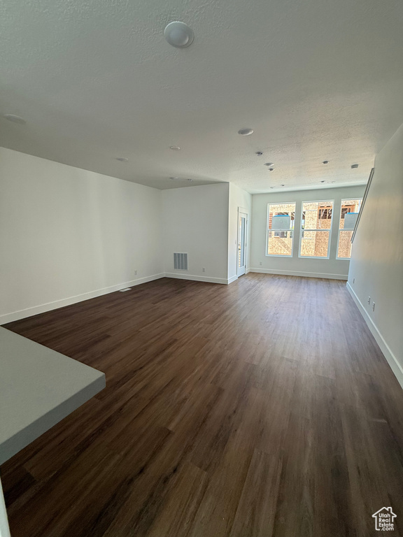 Unfurnished living room with dark wood-style flooring and baseboards