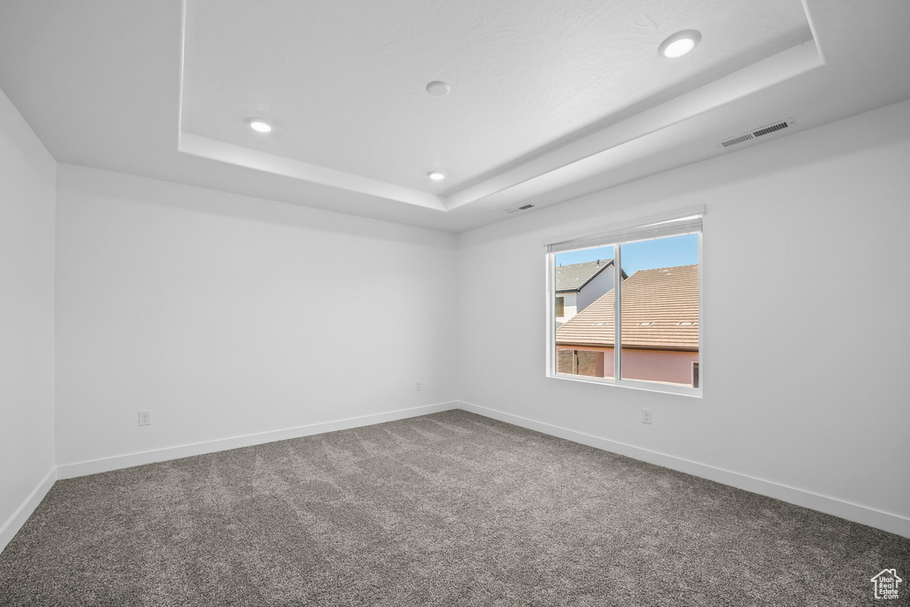 Carpeted empty room featuring a tray ceiling, recessed lighting, and baseboards