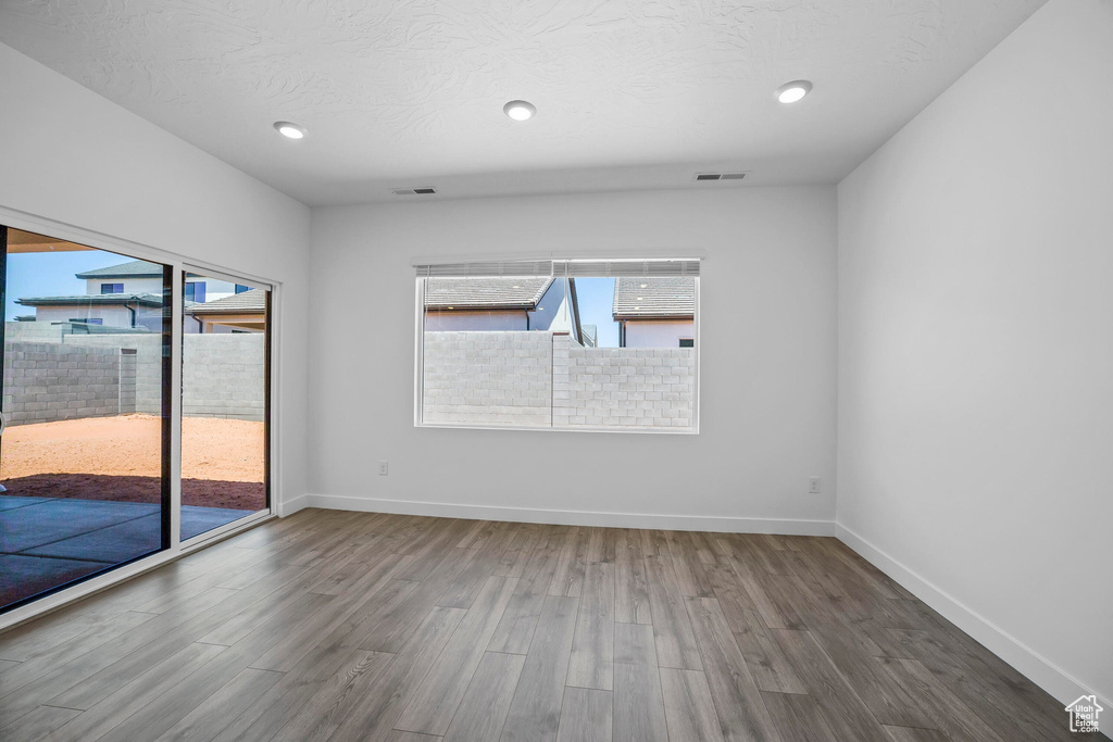 Spare room featuring healthy amount of natural light, wood finished floors, baseboards, and recessed lighting