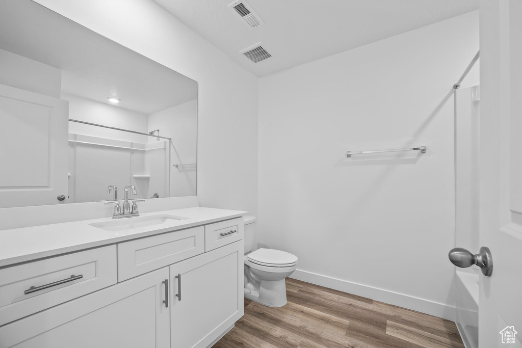 Bathroom with toilet, wood finished floors, vanity, and baseboards