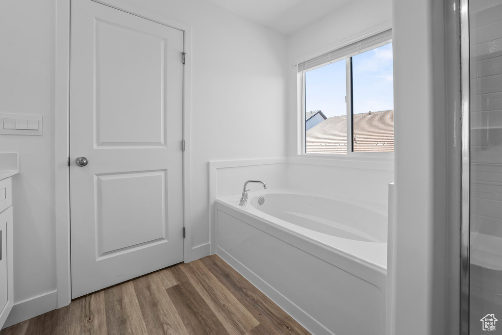 Full bath featuring a bath, wood finished floors, vanity, and baseboards