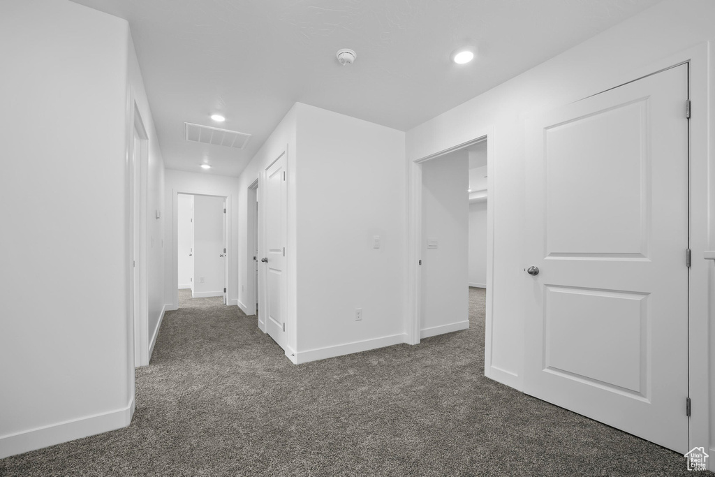 Hall featuring dark carpet, baseboards, and recessed lighting