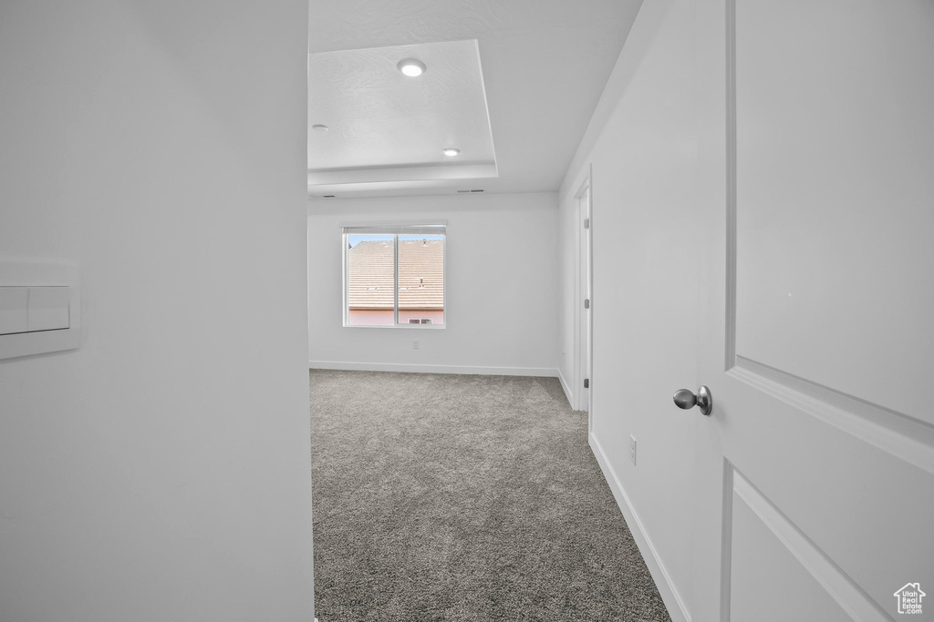 Empty room with carpet flooring, a tray ceiling, baseboards, and recessed lighting