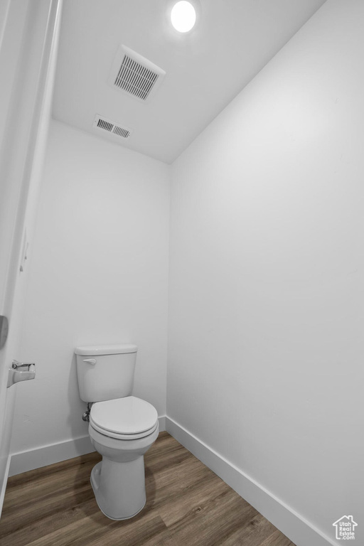 Bathroom with baseboards, wood finished floors, and toilet