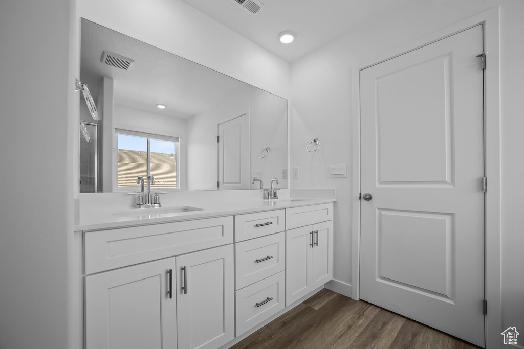 Full bath with double vanity and wood finished floors
