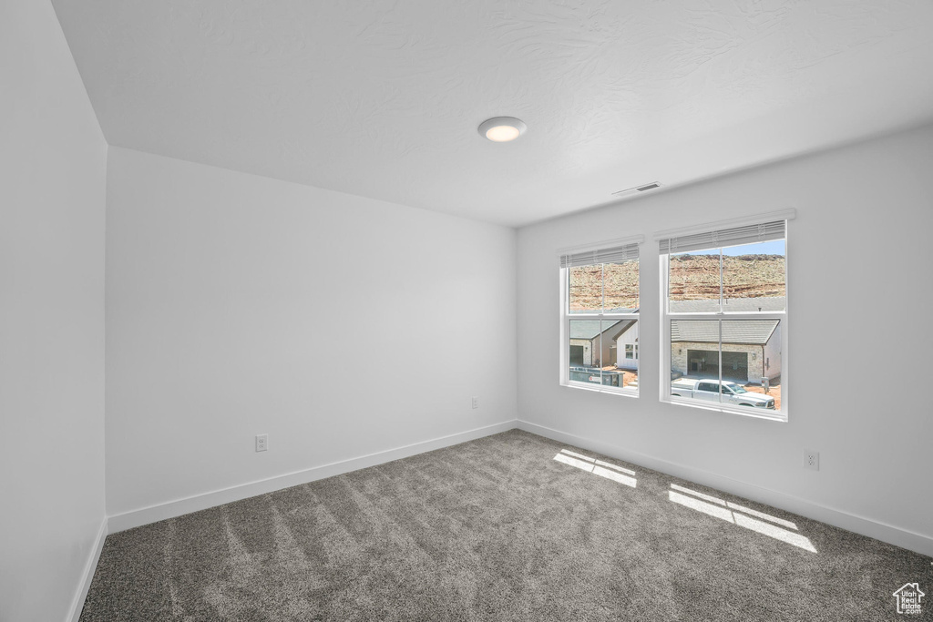 Carpeted spare room featuring baseboards