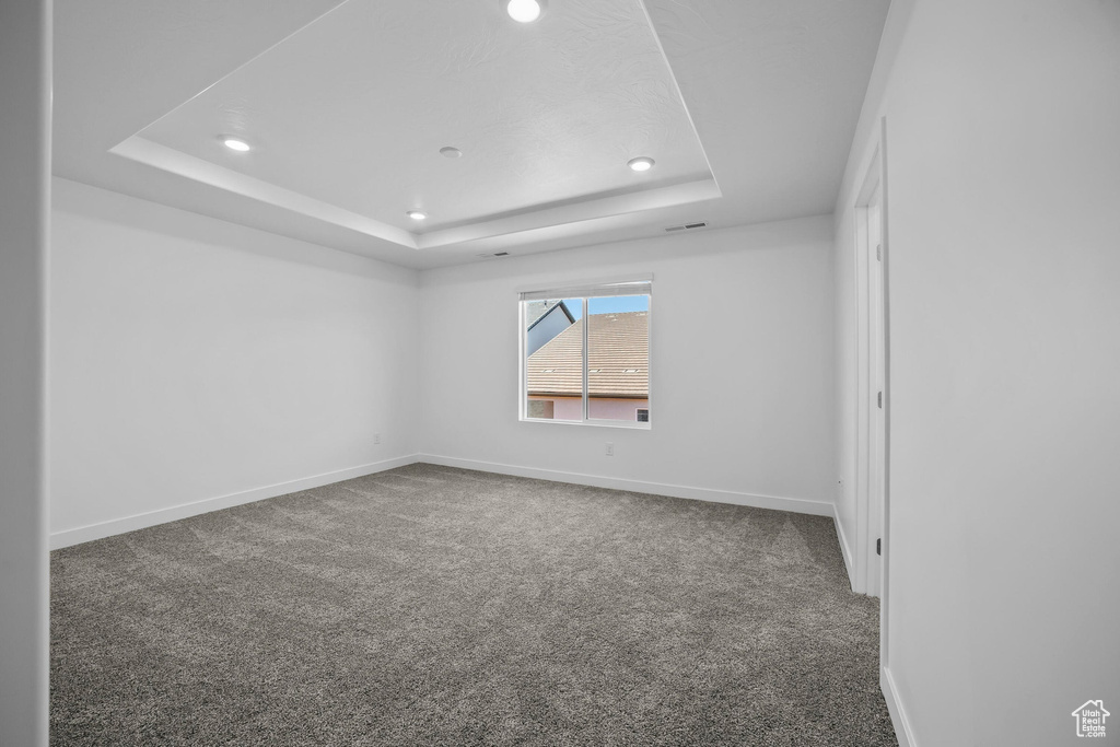 Spare room featuring a raised ceiling, carpet floors, recessed lighting, and baseboards