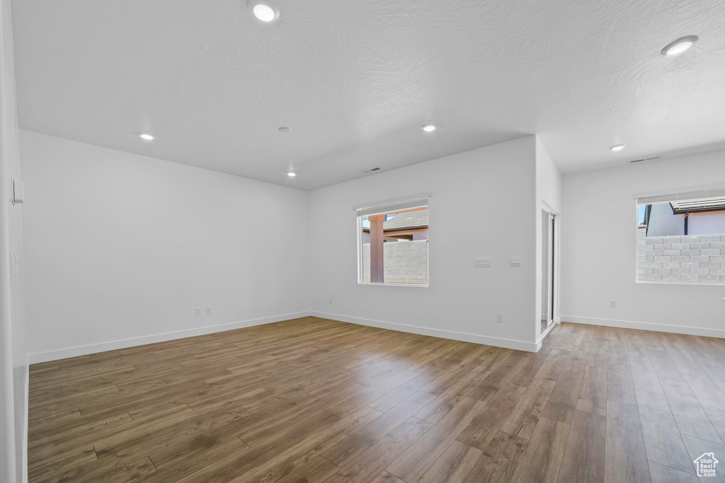 Unfurnished room featuring wood finished floors, healthy amount of natural light, recessed lighting, and baseboards