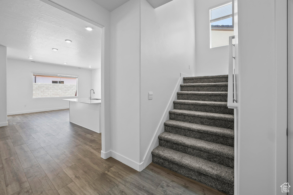 Stairs with baseboards, wood finished floors, and recessed lighting