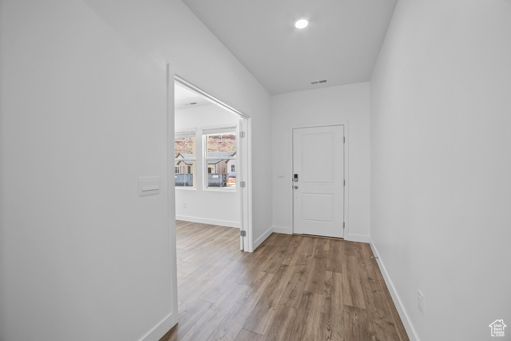 Corridor with wood finished floors, baseboards, and recessed lighting