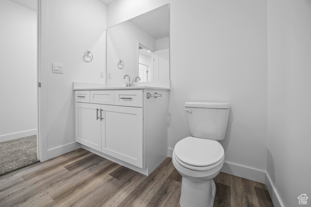 Bathroom with vanity, toilet, baseboards, and wood finished floors