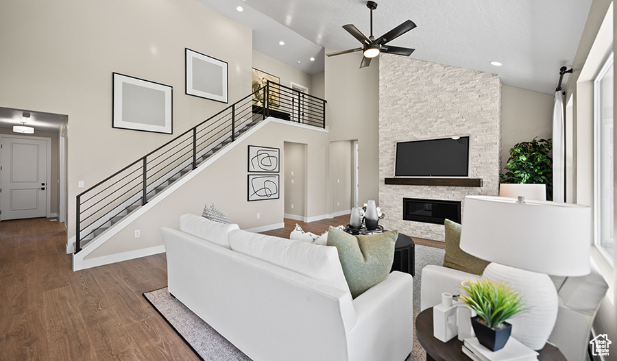 Living room with recessed lighting, wood finished floors, a ceiling fan, stairway, and high vaulted ceiling