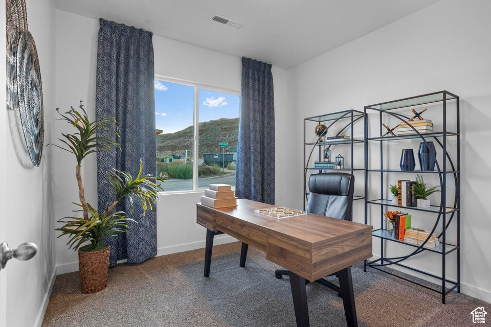 Carpeted home office featuring baseboards