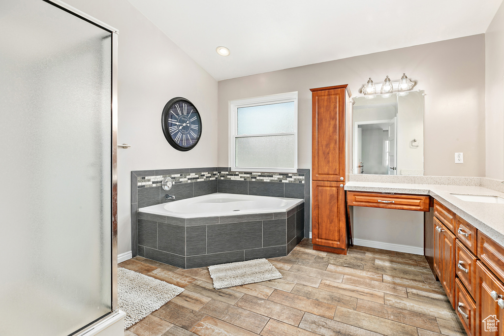 Full bath featuring vanity, a garden tub, a stall shower, and wood finished floors
