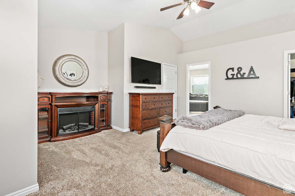 Carpeted bedroom with lofted ceiling, baseboards, a fireplace, ceiling fan, and ensuite bath
