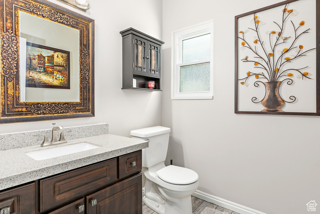 Bathroom featuring toilet, vanity, and baseboards