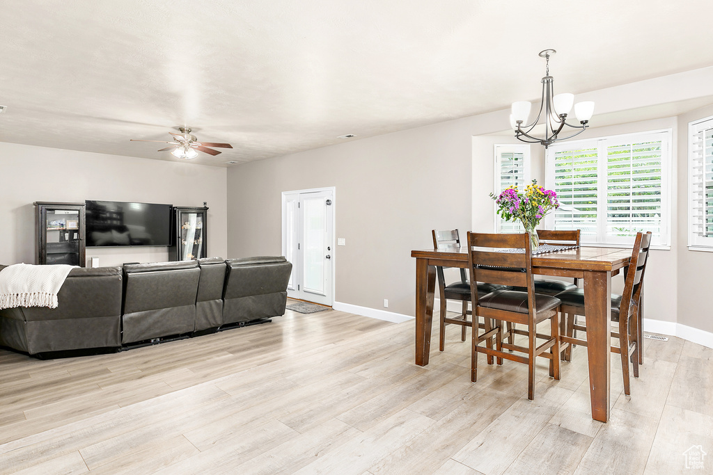 Dining space with a chandelier, light wood-style floors, baseboards, and ceiling fan