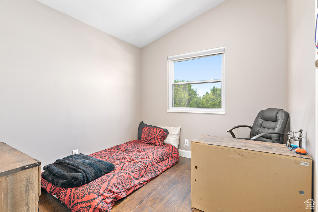 Bedroom with lofted ceiling, dark wood finished floors, and baseboards