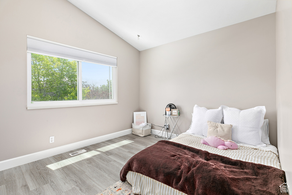 Bedroom with lofted ceiling, wood finished floors, and baseboards