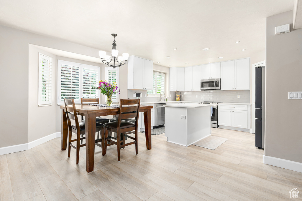 Dining area featuring a chandelier, baseboards, light wood finished floors, and recessed lighting