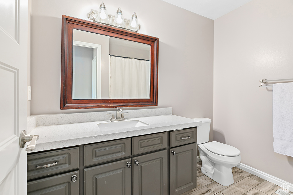 Bathroom with vanity, wood finished floors, toilet, and baseboards