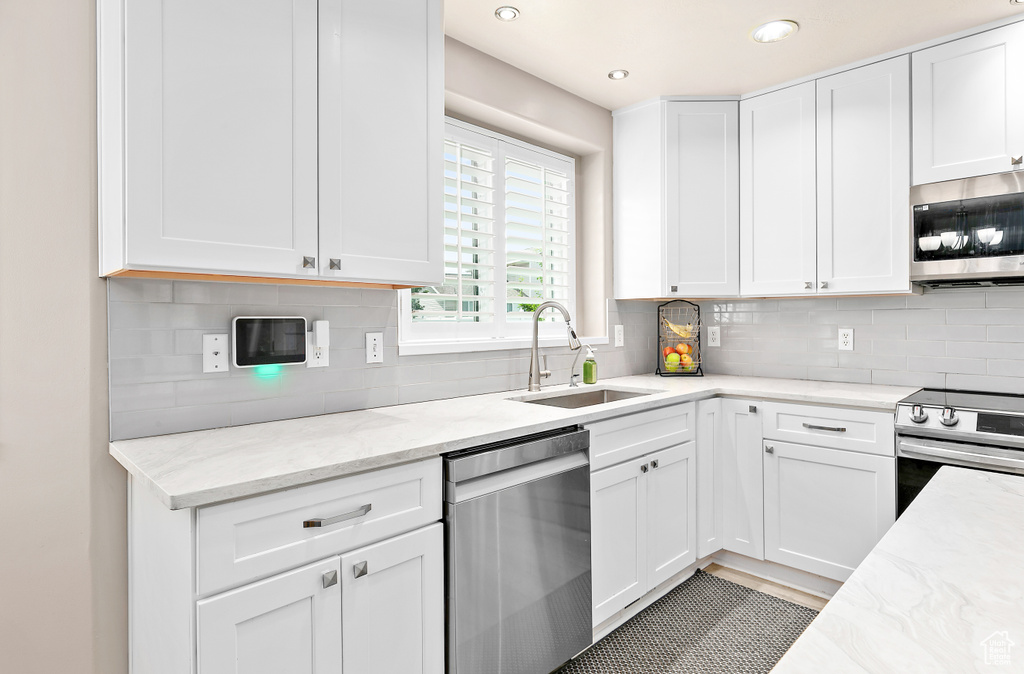 Kitchen featuring appliances with stainless steel finishes, a sink, white cabinetry, and recessed lighting