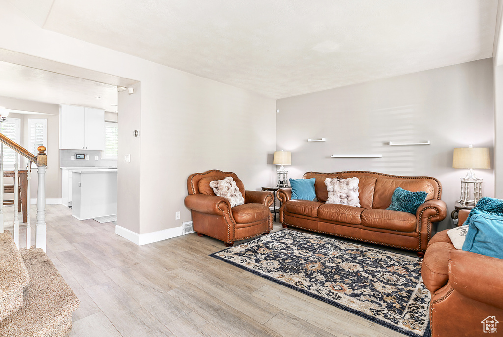 Living area featuring light wood-style flooring, baseboards, and stairway