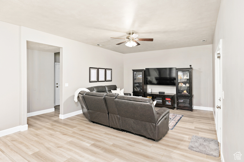 Living area with a ceiling fan, light wood-style floors, and baseboards