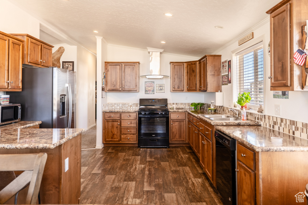 Kitchen with black appliances, wall chimney exhaust hood, brown cabinets, a sink, and dark wood-style floors