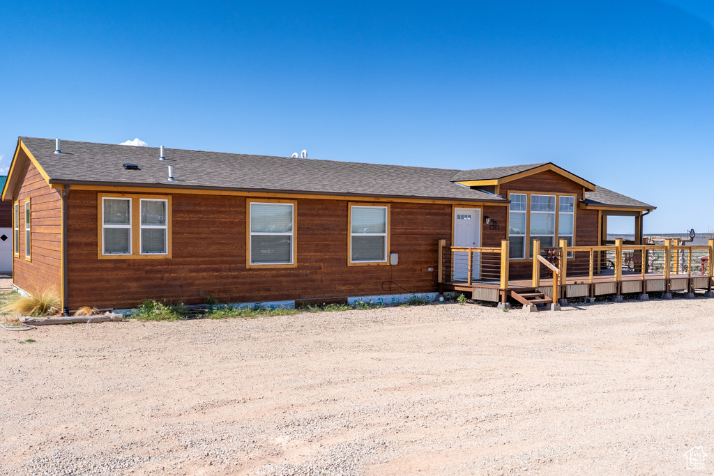 Back of property featuring roof with shingles and a wooden deck