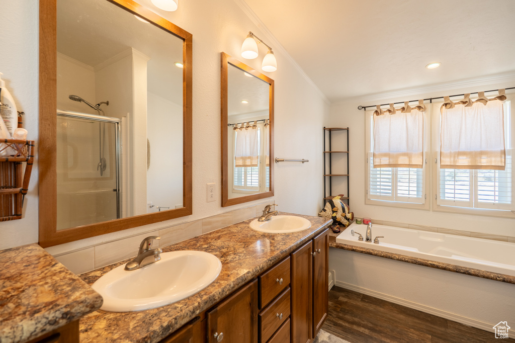 Full bath featuring wood finished floors, a stall shower, a garden tub, and double vanity