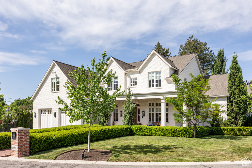 View of front of property with brick siding, a front yard, and a shingled roof