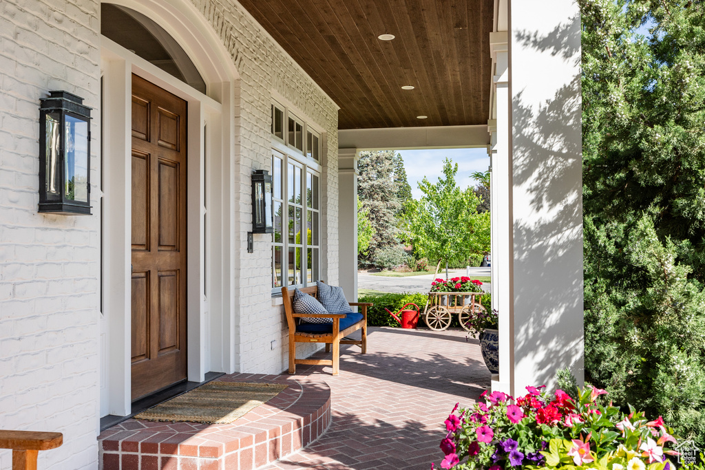 View of exterior entry with covered porch and brick siding