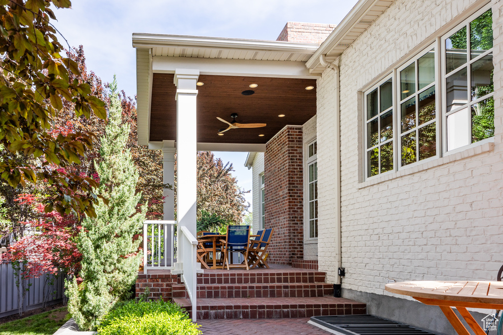 Doorway to property with ceiling fan, a porch, and brick siding