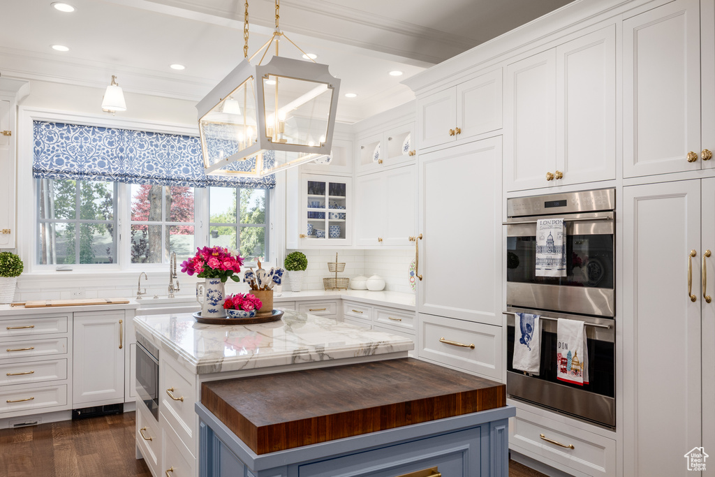 Kitchen with stainless steel appliances, wooden counters, a chandelier, white cabinets, and a kitchen island
