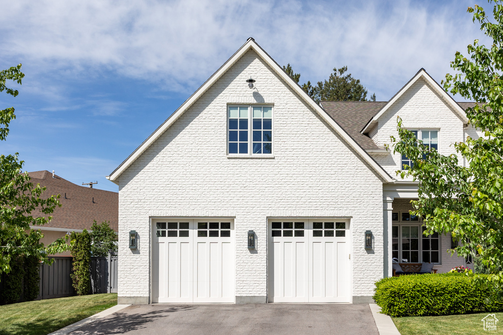 View of front of house featuring a garage, driveway, and brick siding