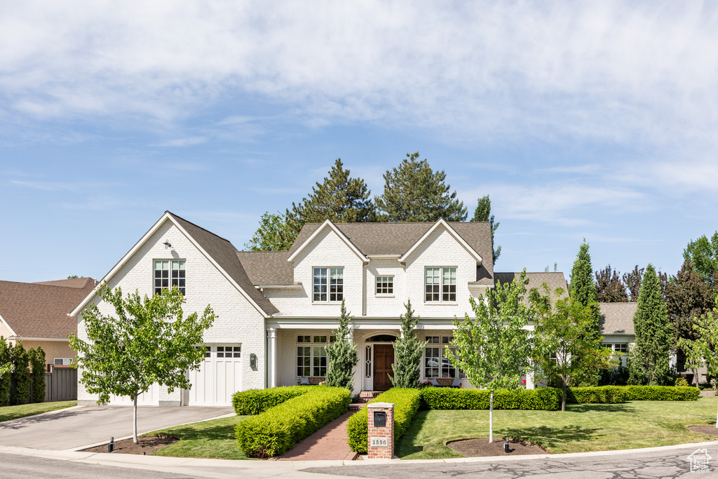 View of front facade with concrete driveway, a garage, brick siding, a front yard, and a shingled roof