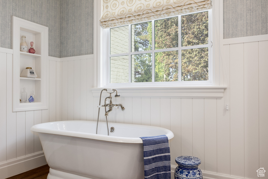 Full bathroom featuring a freestanding bath, a wainscoted wall, a decorative wall, and wood finished floors