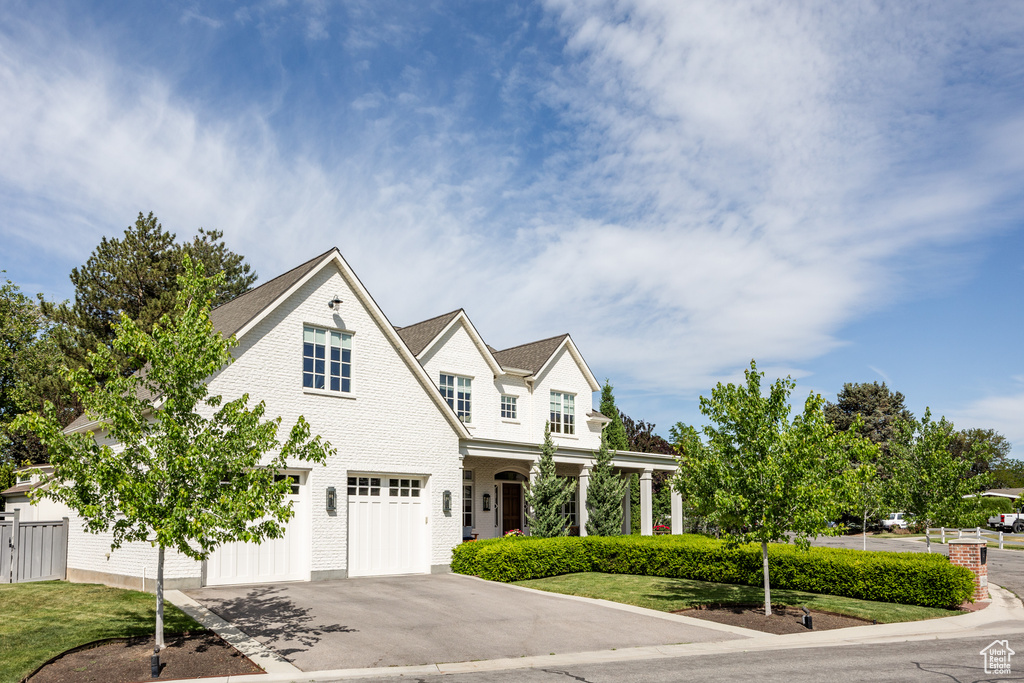 Shingle-style home with concrete driveway, an attached garage, and a porch