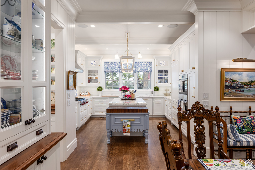 Kitchen with dark wood-style flooring, white cabinets, glass insert cabinets, light countertops, and a chandelier