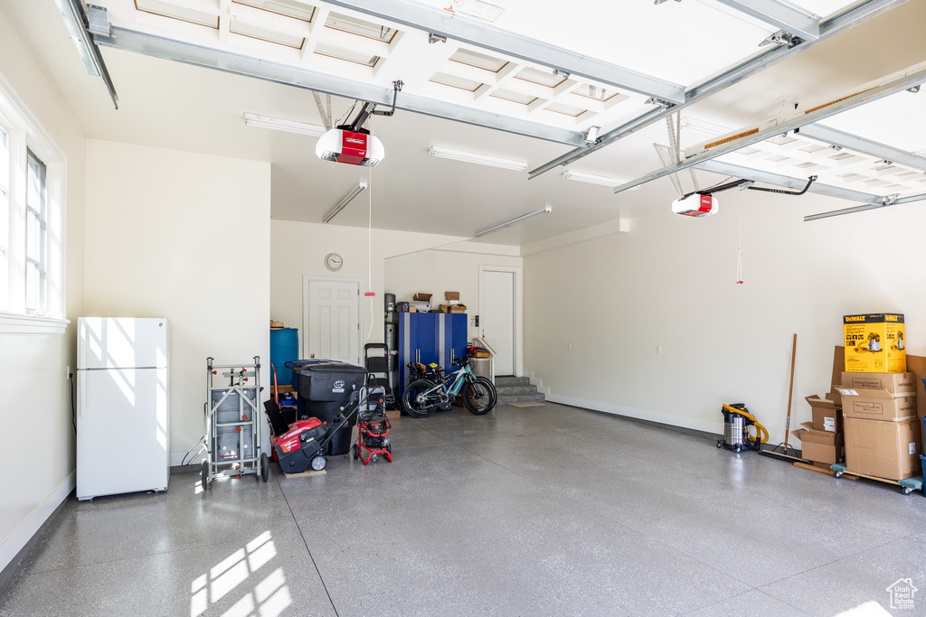 Garage featuring freestanding refrigerator, a garage door opener, and baseboards